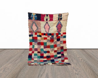 Puede incluir: Una alfombra marroquí colorida con un patrón geométrico en tonos de rojo, rosa, azul, verde y blanco. La alfombra tiene forma cuadrada y está hecha de lana.
