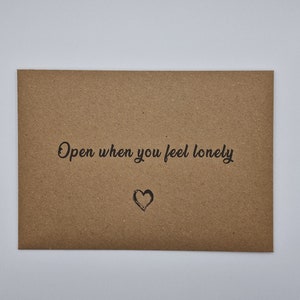 K&ouml;nnte beinhalten: Ein brauner Umschlag mit dem Text "Open when you feel lonely" und einem kleinen gezeichneten Herzen.