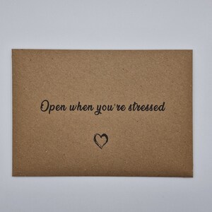 K&ouml;nnte beinhalten: Ein brauner Papierumschlag mit dem Text "Open when you're stressed" und einem kleinen gezeichneten Herzen.