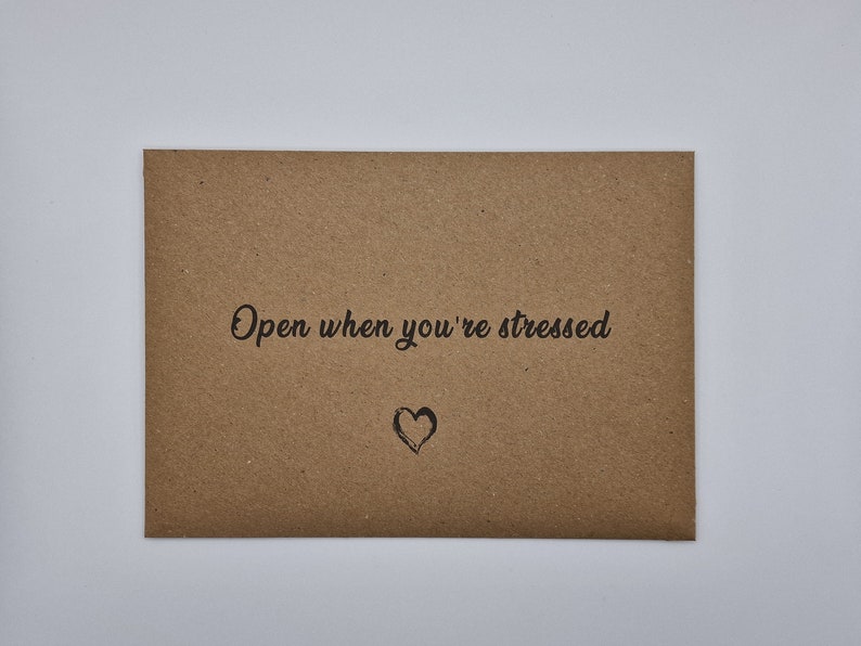 K&ouml;nnte beinhalten: Ein brauner Papierumschlag mit dem Text "Open when you're stressed" und einem kleinen gezeichneten Herzen.
