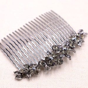 May include: A silver hair comb with a decorative design of black rhinestones in the shape of flowers.