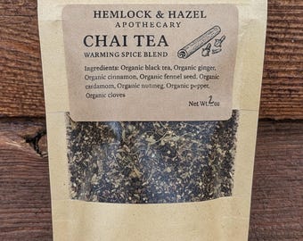 May include: A kraft paper bag of Chai Tea from Hemlock & Hazel Apothecary. The label reads "Chai Tea Warming Spice Blend" with a cinnamon stick illustration. The ingredients include organic black tea, ginger, cinnamon, fennel seed, cardamom, nutmeg, pepper, and cloves. Net weight: 2 oz.