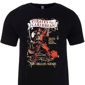 May include: Black t-shirt with a graphic print of a pirate holding a sword and a treasure chest. The graphic includes the text "Pirates of the Caribbean" and "New Orleans Square".