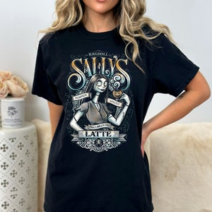 Puede incluir: Camiseta negra con un gr&aacute;fico de Sally de Pesadilla antes de Navidad. El gr&aacute;fico muestra a Sally sosteniendo un latte de calabaza especiado y el texto "Ragdoll Sally's Pumpkin Spiced Latte Frogg's Breath Free".