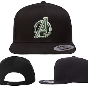 Può includere: Cappellino snapback nero con il logo degli Avengers ricamato in verde. Il cappellino ha una visiera piatta e una chiusura a scatto regolabile. Il cappello è realizzato in un materiale resistente.