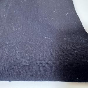 Peut inclure: Gros plan sur une section de tissu bleu marine foncé. Le tissu a un tissage texturé et un aspect légèrement usé. Le bord du tissu est effiloché, montrant le bord brut du matériau. Le tissu est probablement utilisé pour les vêtements ou la décoration intérieure.