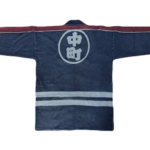 Puede incluir: Una chaqueta de estilo japonés azul oscuro y burdeos con un círculo blanco en la espalda que dice "中町" en caracteres japoneses.