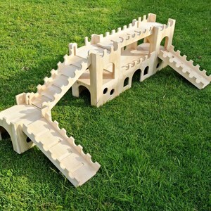 May include: A wooden castle playset with multiple levels and ramps. The castle is made of natural wood and has a rustic look. The playset is perfect for children to use their imagination and have fun.