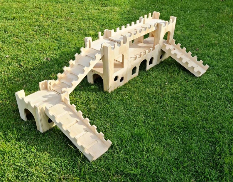 May include: A wooden castle playset with multiple levels and ramps. The castle is made of natural wood and has a rustic look. The playset is perfect for children to use their imagination and have fun.