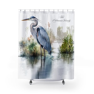 May include: A shower curtain featuring a watercolor illustration of a Great Blue Heron standing in water. The bird has blue-gray feathers and a long beak. The text "The Edmann Family" is printed in a script font.