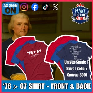 Op de afbeelding: Een display van T-shirts met historische thema's. Eén bordeauxrood shirt heeft de tekst "'76 > 67" en "Jefferson". Een ander marineblauw shirt heeft een citaat over gelijkheid. De shirts zijn gestapeld voor een portret.
