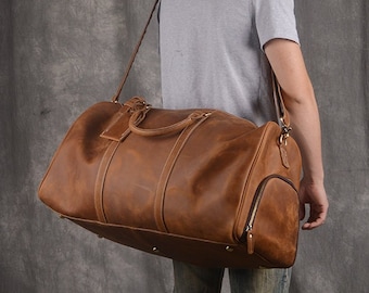 May include: A brown leather duffel bag with a shoulder strap. The bag has a zippered pocket on the side and a top handle.