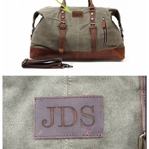 May include: A canvas duffel bag with brown leather accents, straps, and handles. The bag has a brown leather base and a detachable shoulder strap. A leather patch with the name "Jack" is visible. The bag is designed for personalization.