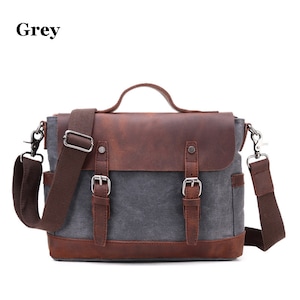 May include: Grey messenger bag with a brown leather flap and accents. The bag has a handle, adjustable shoulder strap, and two buckle closures. The word "Grey" is printed in the upper left corner.