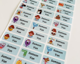 Op de afbeelding: Een vel blauwe en witte labels met cartoonfiguren. De labels zeggen "Samson Van" in zwarte tekst.