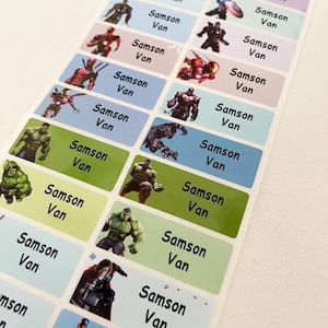 May include: A sheet of colorful labels with superhero images and the name "Samson Van" repeated on each label. The labels are rectangular and have a glossy finish.