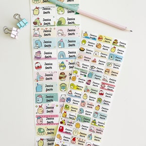 May include: A set of colorful name labels featuring a variety of cute cartoon characters. The labels are rectangular and have a white background with a colorful border. The name "Jessica Smith" is printed on each label.