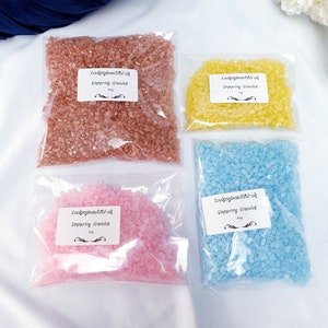 May include: Four bags of bath salts in different colours: pink, blue, yellow, and brown. Each bag has a label that says "Lookingbeautiful-uk" and "Singering Granules".