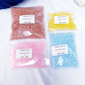 May include: Four bags of bath salts in different colours: pink, yellow, blue, and a light brown colour. Each bag has a label that says "Lookingbeautiful-uk" and "Simmering Granules".