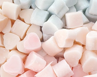 May include: A close-up of a pile of heart-shaped soap bars in various shades of pink and blue. The soap bars are arranged in a random pattern, creating a visually appealing display.