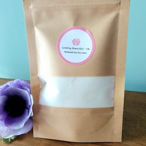 May include: A brown paper bag with a white label that says "Looking Beautiful - UK Handmade Soy Wax Melts". The label has a pink rose design.