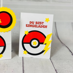 Puede incluir: Una tarjeta blanca con el texto "DU BIST EINGELADEN" en negro. La tarjeta presenta una Pok&eacute;bola roja y blanca con un rayo amarillo y estrellas amarillas.