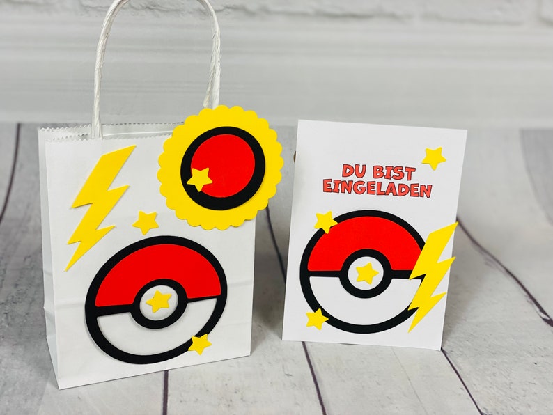 Puede incluir: Una bolsa de regalo de papel blanco con una estrella amarilla, un rayo amarillo y un dise&ntilde;o de Pok&eacute; Ball rojo y blanco. La bolsa est&aacute; atada con una cinta amarilla. Una tarjeta blanca con una estrella amarilla, un rayo amarillo y un dise&ntilde;o de Pok&eacute; Ball rojo y blanco dice "Du bist eingeladen" en texto negro.