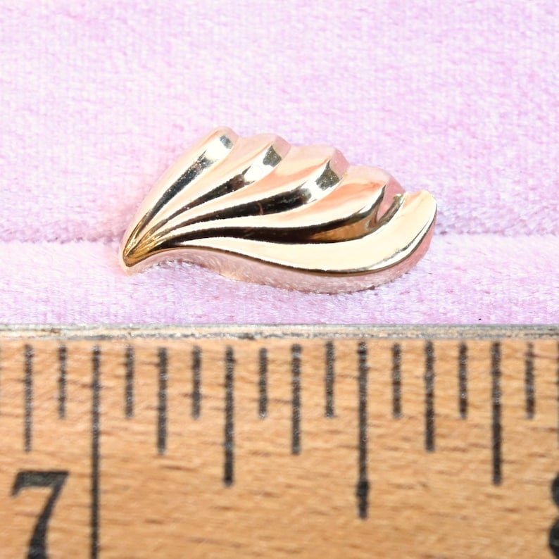 Puede incluir: Un pendiente de metal dorado con un dise&ntilde;o en forma de abanico. El pendiente mide aproximadamente 2,5 cm de largo.