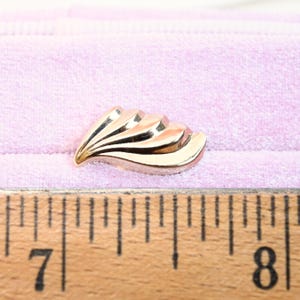 Puede incluir: Un pendiente de metal dorado con un dise&ntilde;o en forma de abanico. El pendiente mide aproximadamente 2,5 cm de largo.