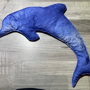 May include: A blue dolphin-shaped pillow with a white and blue marbled pattern.