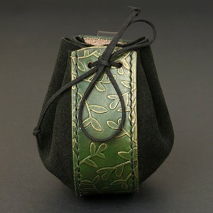 May include: A small green leather pouch with a black drawstring closure. The pouch is decorated with a leafy pattern.