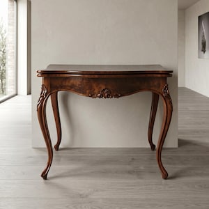 Könnte beinhalten: Ein dunkelbrauner Tisch im antiken Stil mit rechteckiger Platte und geschwungenen Beinen. Der Tisch weist verzierte Schnitzereien an der Zarge und den Beinen auf, die ein klassisches Design zeigen. Der Tisch ist aus Holz und hat eine glänzende Oberfläche.