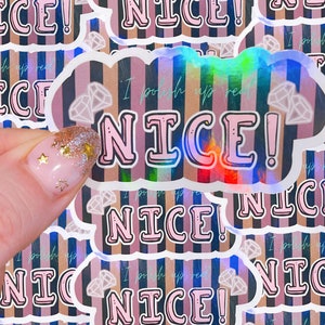 May include: A close-up of a holographic sticker with pink and black stripes. The sticker says "I polish up real nice!" in pink letters with a diamond shape in the background.