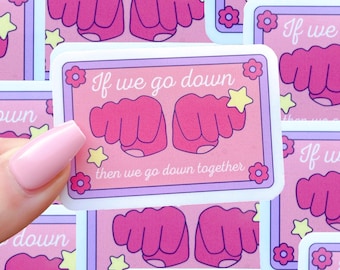 May include: Pink and purple sticker with the text "If we go down, then we go down together" and a cartoon image of two pink fists bumping together. The sticker has a white border and a white background.