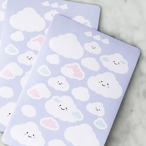 May include: Three sheets of stickers featuring various white clouds with happy faces on a light purple background. Some clouds have pink or blue accents.
