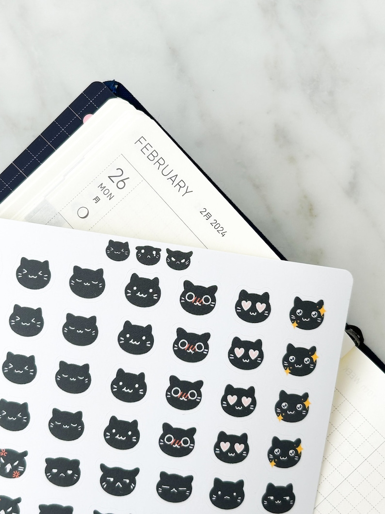 May include: A sheet of black cat stickers with different expressions, including hearts, stars, and sleepy eyes. The stickers are on a white background.