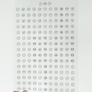 May include: A sheet of clear stickers with a variety of black and white emoji faces. The emojis include happy, sad, surprised, and angry faces.