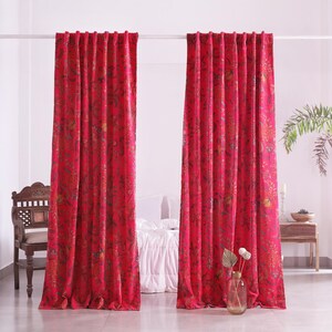 K&ouml;nnte beinhalten: Zwei rote Vorh&auml;nge mit floralem Muster, die an einer wei&szlig;en Stange h&auml;ngen. Die Vorh&auml;nge bestehen aus einem dicken Stoff und haben ein detailliertes Design mit verschiedenen Farben. Ein Holzstuhl und ein Beistelltisch sind im Hintergrund zu sehen.
