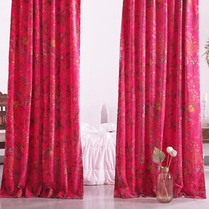 K&ouml;nnte beinhalten: Hellrosa Vorh&auml;nge mit floralem Muster. Die Vorh&auml;nge h&auml;ngen vor einer wei&szlig;en Wand, mit einem Holzstuhl und einem kleinen Tisch. Eine Vase mit Blumen steht vor den Vorh&auml;ngen.