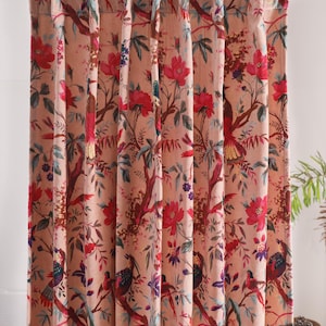 May include: Peach-coloured curtain panel with a floral and bird pattern. The design features red flowers, green leaves, and birds perched on branches. The curtain is hanging from a rod and has a pleated top.