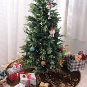 Puede incluir: Un &aacute;rbol de Navidad artificial decorado con adornos y una figura de Pap&aacute; Noel. El &aacute;rbol se encuentra sobre una falda de &aacute;rbol marr&oacute;n, rodeado de regalos envueltos y pi&ntilde;as. Tambi&eacute;n hay una bolsa de regalo a cuadros y flores.