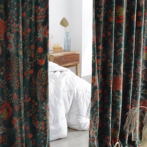 Könnte beinhalten: Dunkelgrüne Samtvorhänge mit einem Blumenmuster in Rot- und Orangetönen. Die Vorhänge hängen vor einem Bett mit einer weißen Bettdecke. Ein Weidenkorb mit Obst steht auf dem Boden.