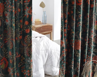 May include: Dark green velvet curtains with a floral pattern in shades of red and orange. The curtains are hanging in front of a bed with a white comforter. A wicker basket with fruit sits on the floor.