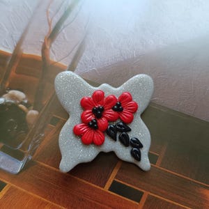 Broche de borboleta cinza feito à mão: joia de inseto com flor vermelha de argila de polímero