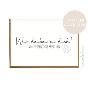 May include: A white card with the text "Wir denken an dich!" and "VON HERZEN GUTE BESSERUNG!" in black script, along with a small clover illustration. The card has a brown border and a beige circle with "DIGITALER DOWNLOAD" on it.