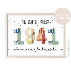 Puede incluir: Un cartel enmarcado con el texto "Ein Guter Jahrgang 1941 Herzlichen Glückwunsch." Los números en "1941" están rellenos con imágenes de billetes en euros. El cartel tiene un fondo blanco y un marco de madera clara.