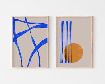 May include: Two framed abstract art prints with a beige background. The print on the left features blue lines in a criss-cross pattern. The print on the right features blue vertical lines and a yellow circle.