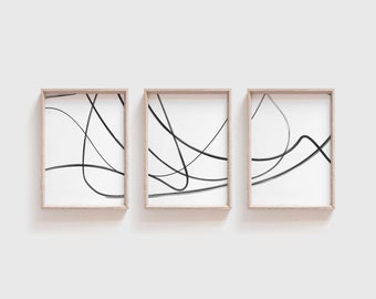 May include: Set of three framed abstract art prints. Each print features black lines on a white background, with a minimalist design. The frames are a light wood color, adding a natural touch to the artwork. Ideal for modern home decor.