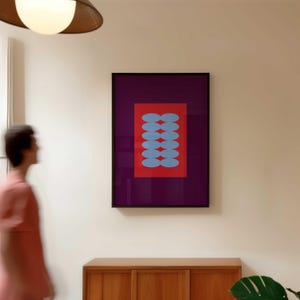Puede incluir: Una impresión artística abstracta enmarcada. Presenta un rectángulo rojo con seis formas ovaladas azules dispuestas verticalmente, sobre un fondo morado oscuro. La obra de arte está en un marco negro.