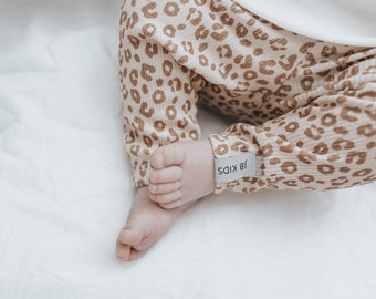 Könnte beinhalten: Ein Baby trägt einen braunen und weißen, gerippten Strampler mit Leopardenmuster und einem weißen Etikett mit der Aufschrift "18 Kids".